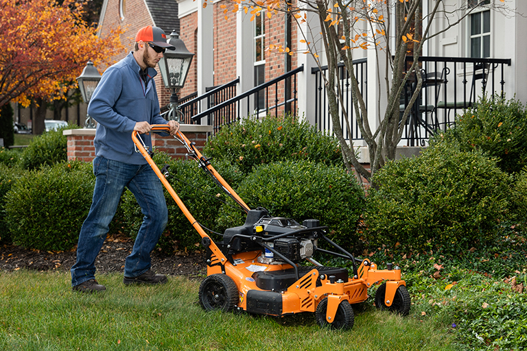 Image of a man pushing a SFCII-30 mower in a yard.